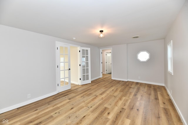 spare room featuring light wood finished floors, baseboards, visible vents, and french doors