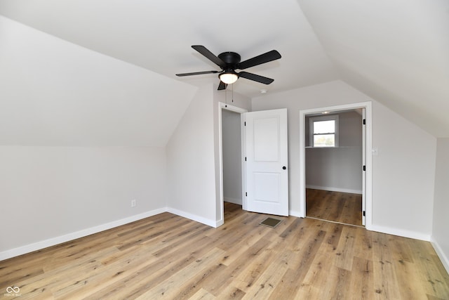 bonus room with lofted ceiling, visible vents, light wood-style flooring, a ceiling fan, and baseboards