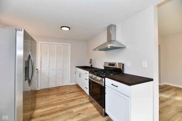 kitchen featuring extractor fan, a sink, white cabinetry, appliances with stainless steel finishes, and light wood-type flooring