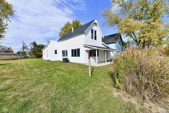 rear view of house with roof with shingles, a patio area, a yard, and central AC unit