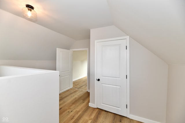 additional living space with lofted ceiling, light wood-style flooring, and baseboards