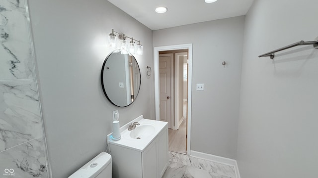 bathroom featuring toilet, marble finish floor, baseboards, and vanity