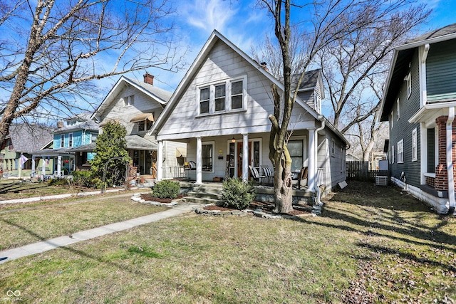 view of front of property with a front lawn, fence, covered porch, and a chimney