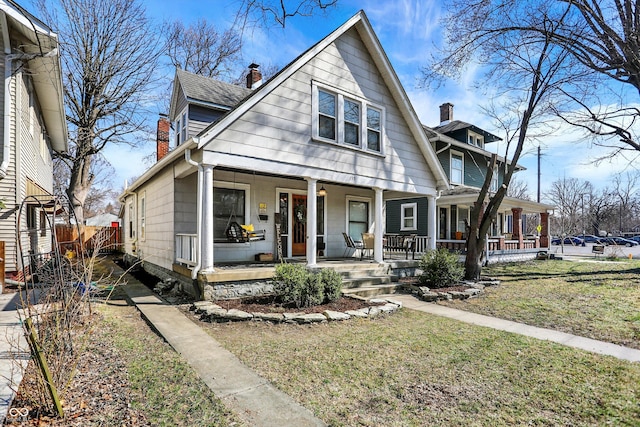 view of front of house featuring a front lawn, fence, roof with shingles, covered porch, and a chimney