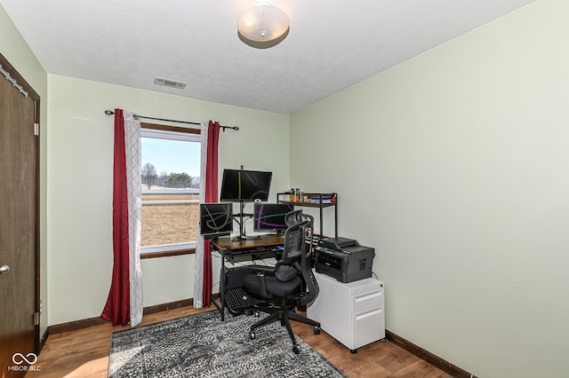 office space with visible vents, a textured ceiling, baseboards, and wood finished floors