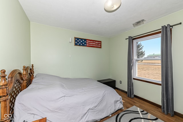 bedroom featuring visible vents, baseboards, and wood finished floors