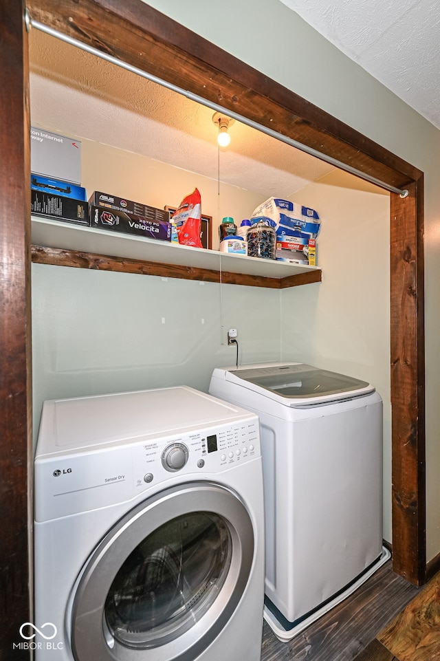 laundry area with laundry area, washing machine and dryer, a textured ceiling, and wood finished floors