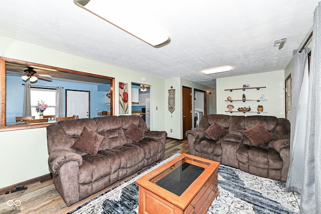 living room with washer / clothes dryer, a textured ceiling, and wood finished floors