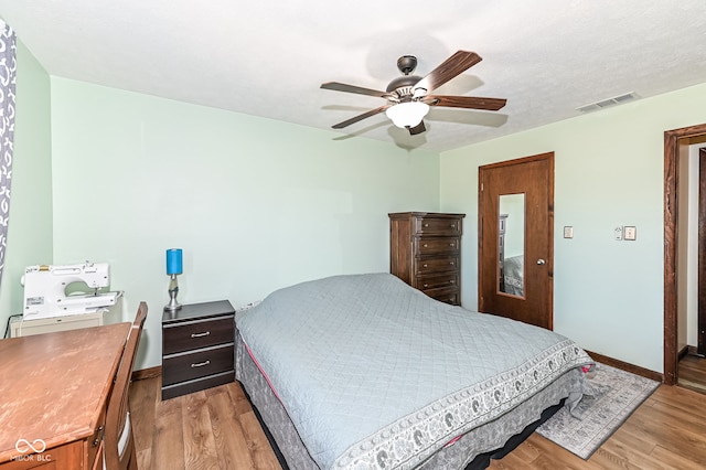 bedroom featuring ceiling fan, light wood-type flooring, visible vents, and baseboards