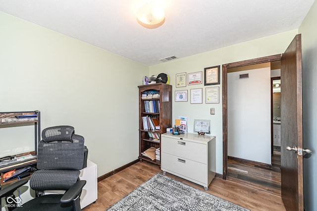 office featuring light wood-type flooring, visible vents, and baseboards