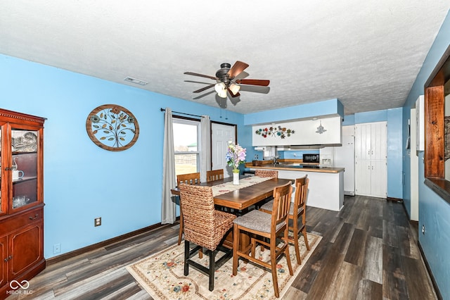 dining space with visible vents, dark wood-type flooring, a ceiling fan, a textured ceiling, and baseboards