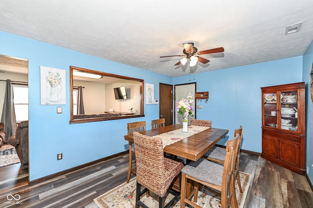 dining area with baseboards, a textured ceiling, visible vents, and wood finished floors