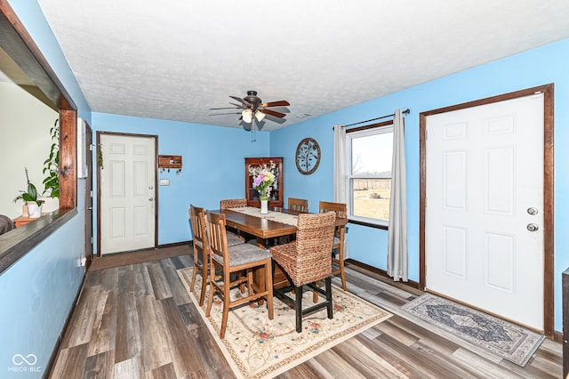 dining room with dark wood finished floors, a textured ceiling, baseboards, and ceiling fan