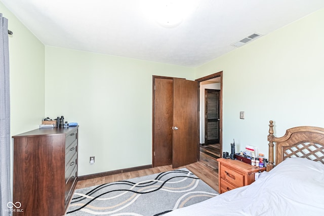 bedroom with light wood-style floors, visible vents, and baseboards