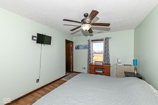 bedroom with a textured ceiling, wood finished floors, a ceiling fan, and baseboards