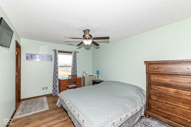 bedroom featuring a textured ceiling, wood finished floors, a ceiling fan, and baseboards