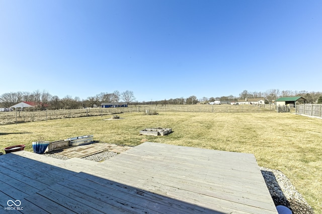 deck with a fenced backyard, a lawn, and a rural view