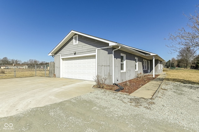 view of property exterior with concrete driveway, fence, and an attached garage