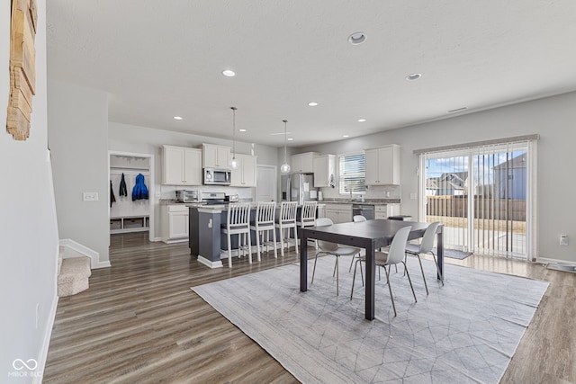 dining room with baseboards, wood finished floors, and recessed lighting