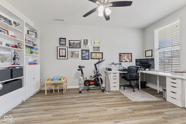 home office with visible vents, light wood-type flooring, a ceiling fan, and baseboards