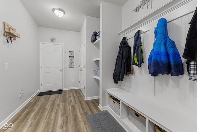 mudroom with a textured ceiling, wood finished floors, and baseboards