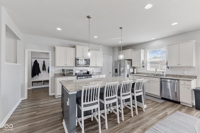 kitchen with wood finished floors, appliances with stainless steel finishes, a kitchen island, and white cabinets