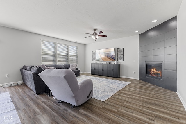 living area with dark wood-style floors, a fireplace, baseboards, and a textured ceiling