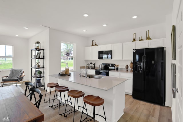 kitchen with black appliances, light wood-style flooring, light countertops, and a sink