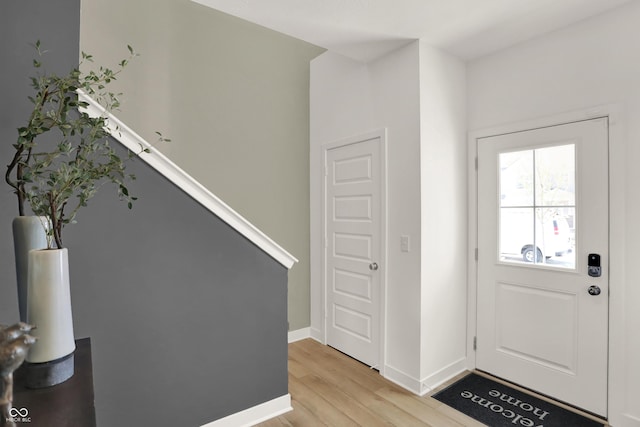 foyer with stairway, light wood-style flooring, and baseboards