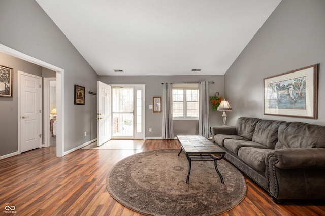 living area featuring high vaulted ceiling, wood finished floors, visible vents, and baseboards