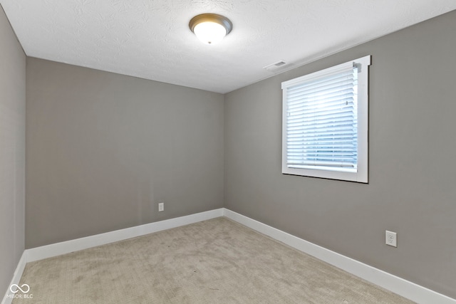 unfurnished room with visible vents, baseboards, a textured ceiling, and carpet floors