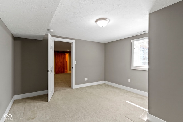 unfurnished bedroom with baseboards, light carpet, a textured ceiling, and visible vents