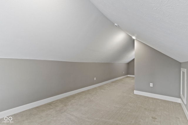 bonus room with light carpet, a textured ceiling, lofted ceiling, and baseboards