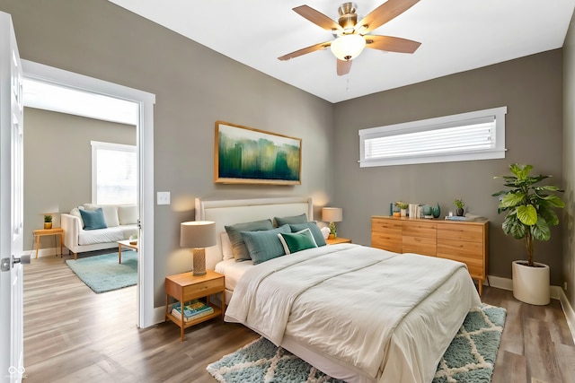 bedroom featuring multiple windows, baseboards, and light wood finished floors