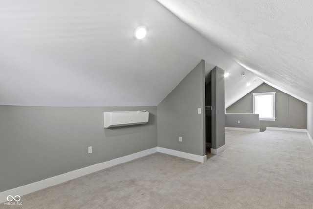 additional living space featuring vaulted ceiling, carpet, baseboards, and a wall mounted AC