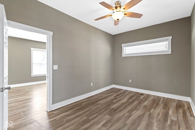 empty room featuring plenty of natural light, wood finished floors, baseboards, and ceiling fan