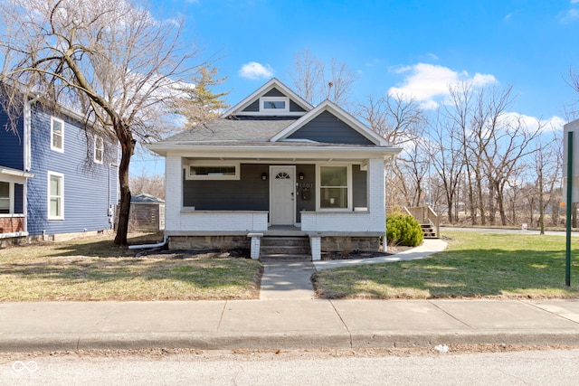 bungalow-style home featuring brick siding, covered porch, and a front lawn