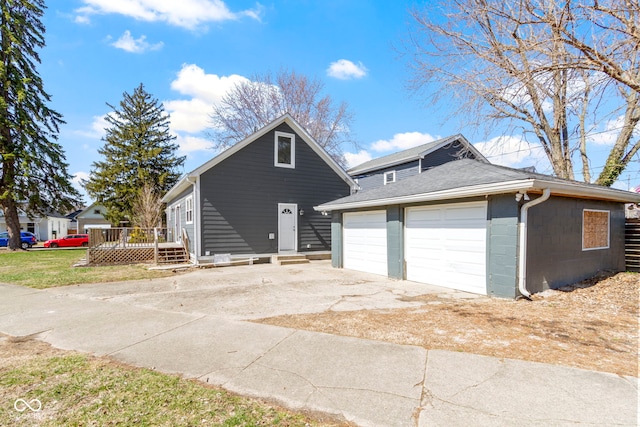 exterior space featuring concrete block siding, an outbuilding, concrete driveway, a garage, and a deck