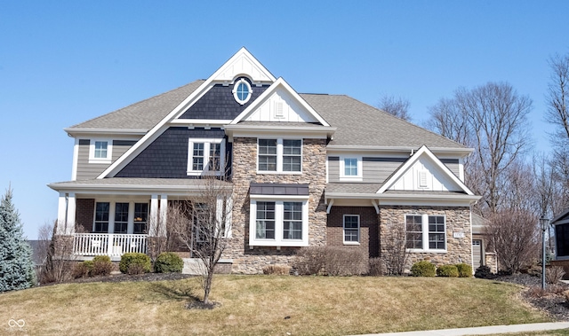 craftsman house featuring a front lawn, covered porch, stone siding, and roof with shingles