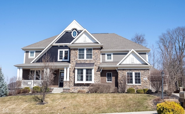 craftsman-style home with stone siding, roof with shingles, and a front yard