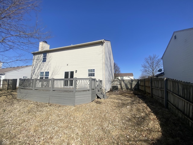 rear view of property with a fenced backyard, a chimney, and a wooden deck