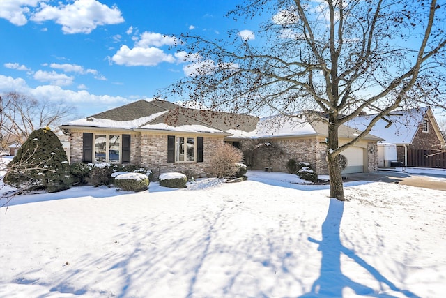 view of front of property featuring a garage, driveway, brick siding, and fence