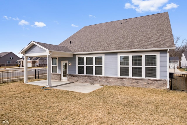 rear view of house featuring a patio, brick siding, a lawn, and fence