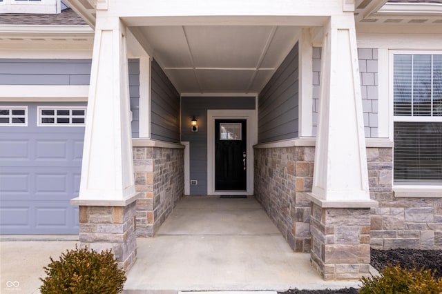 entrance to property featuring a garage and stone siding