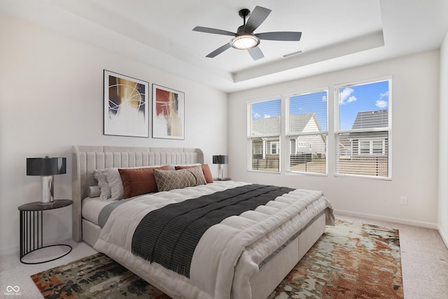 bedroom with baseboards, visible vents, a raised ceiling, a ceiling fan, and carpet floors