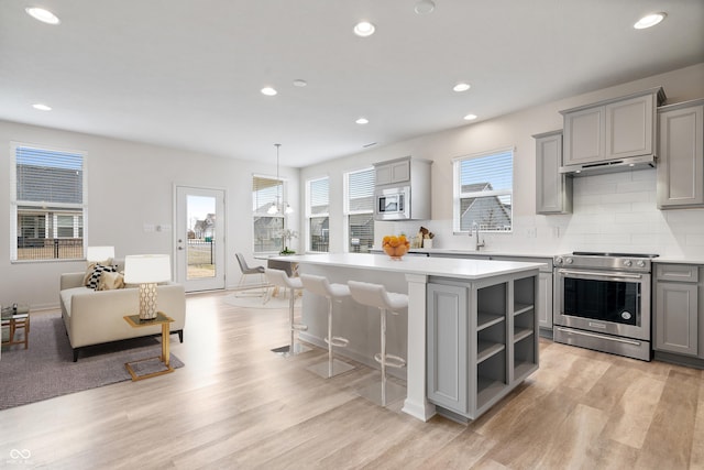 kitchen featuring stainless steel appliances, a center island, light countertops, and gray cabinetry