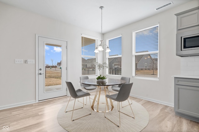 dining room featuring plenty of natural light, an inviting chandelier, visible vents, and light wood-style floors