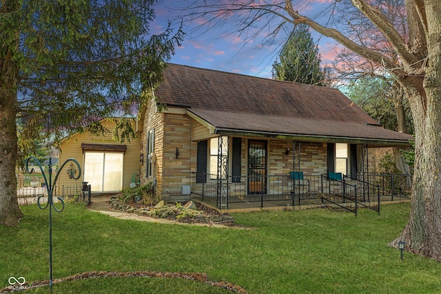 view of front of house with a porch, stone siding, roof with shingles, and a front lawn