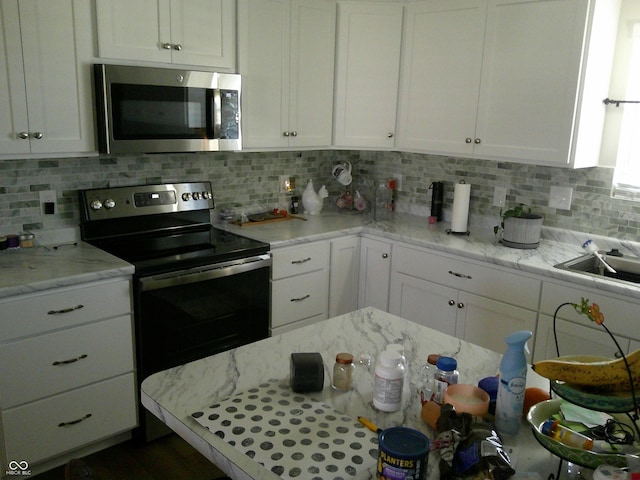 kitchen featuring white cabinets, range with electric cooktop, stainless steel microwave, and tasteful backsplash