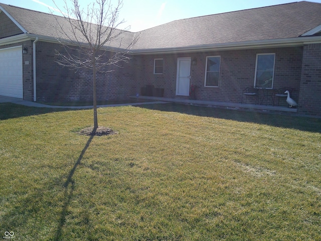 ranch-style house with an attached garage, roof with shingles, a front lawn, and brick siding